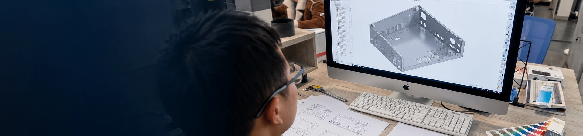 engineer reviewing a custom enclosure CAD model and technical drawings for DFM analysis