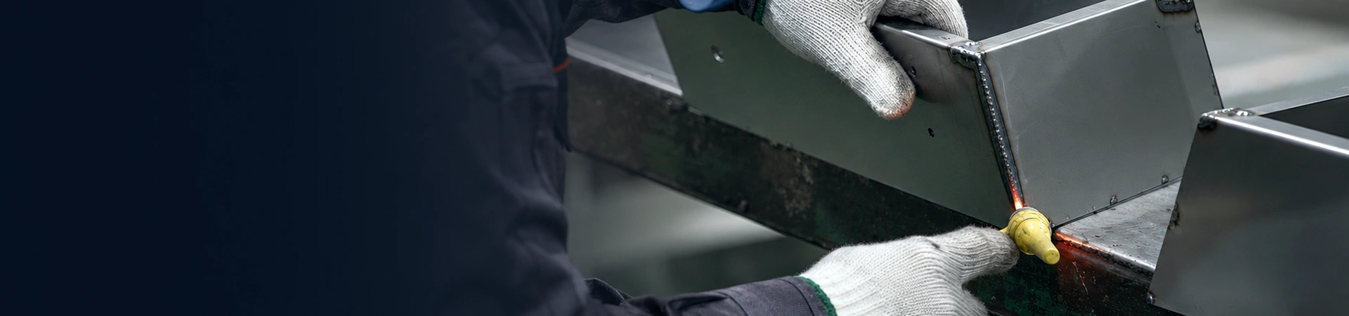 Sheet metal welding and assembly process with worker welding a custom metal enclosure in an industrial workshop